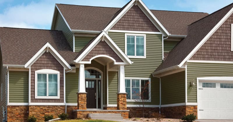 Beautiful green and brown house with a welcoming front porch and multiple gables.