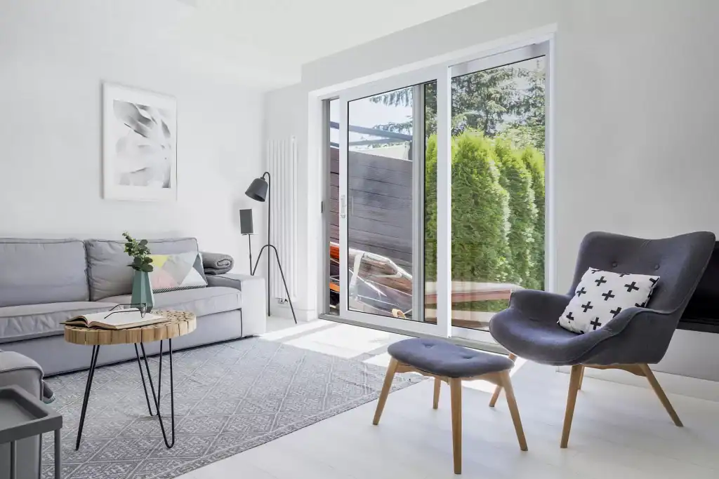 Modern living room with large sliding glass door and outdoor greenery, showcasing Tamar Building Pro.