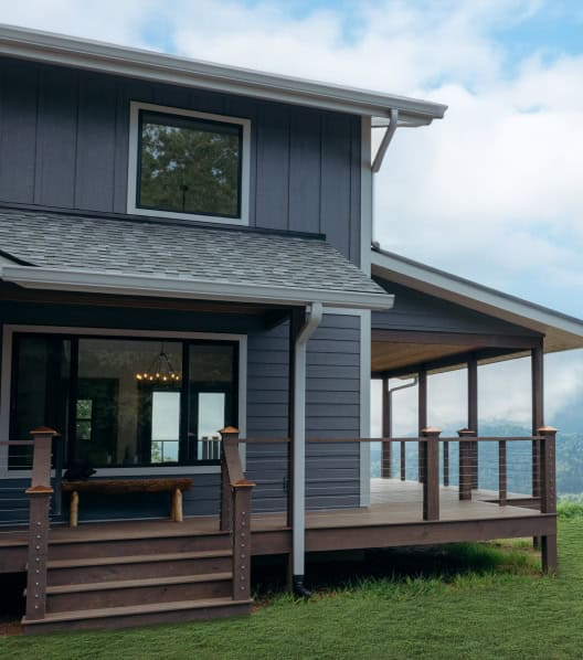 Blue house exterior with wooden deck and railing, showcasing quality building materials from Tamar B.