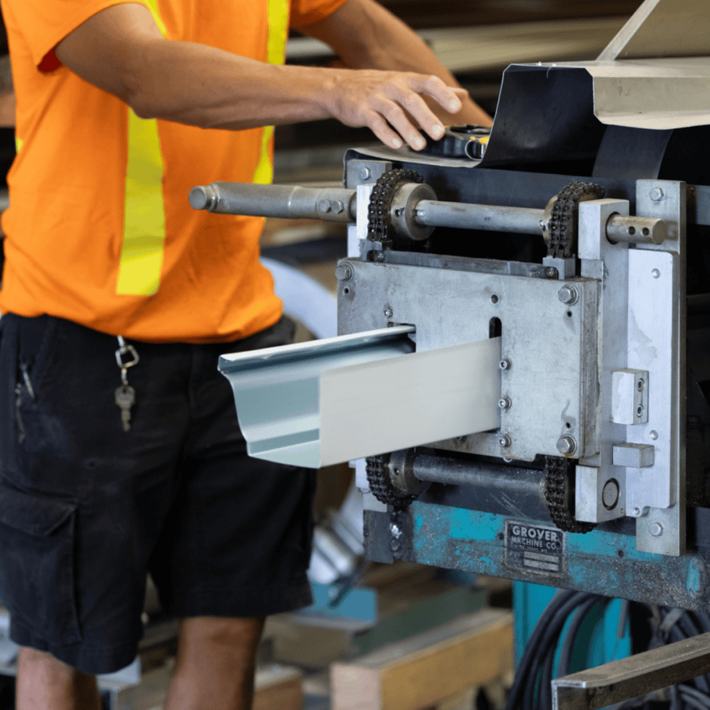 Industrial worker operating metal cutting machine at Tamar Building Products.