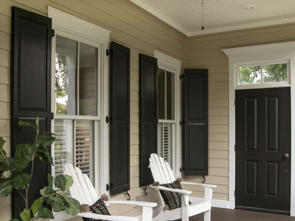 Exterior view of a house with black shutters and white window frames in a residential setting.