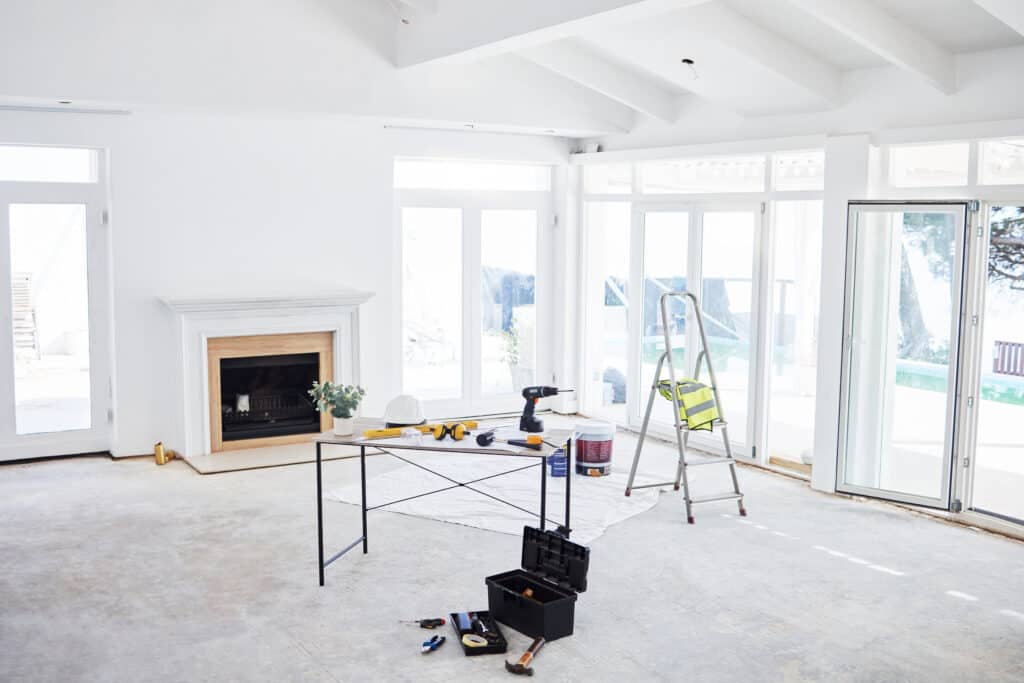 Sunroom with large windows, fireplace, and construction tools in progress.