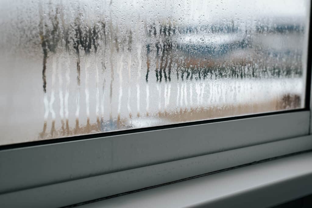 Steam and condensation on a window glass, showing water droplets and streaks.