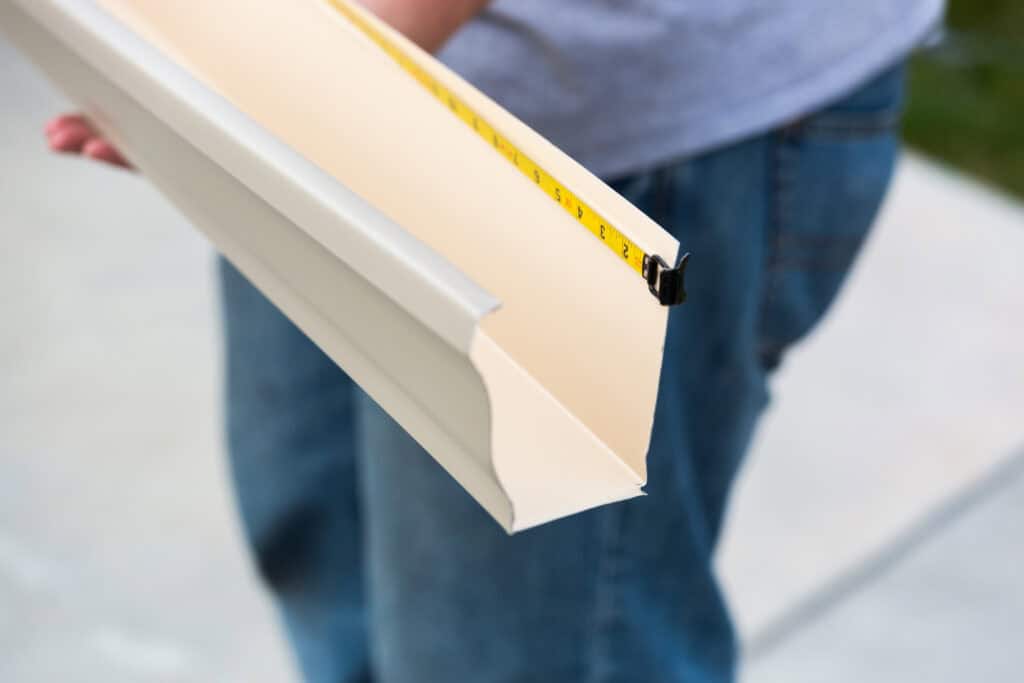 Close-up of a person holding a white measuring tool for building projects.