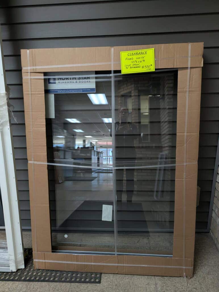 Large glass sliding door with cardboard packaging and clearance sticker.