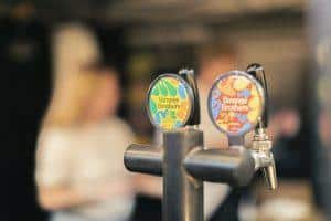Colorful beer tap handles at Taranaki Beer Festival, showcasing local craft beers and lively festival atmosphere.