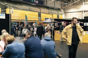 Vibrant indoor scene at the Taranaki Beer Festival with diverse craft beers and lively crowd.