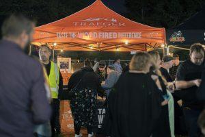 Bright orange Taranaki Beer Festival tent at night, with people enjoying craft beers and food stalls.