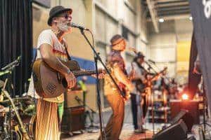 Vibrant live music performance at Taranaki Beer Festival with musicians playing guitars and saxophones.
