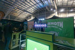 Bright indoor scene at Taranaki Beer Festival showcasing craft beer stalls and festival attendees.