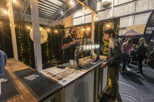 Cool craft beer being poured at Taranaki Beer Festival in NZ, with patrons enjoying local brews.