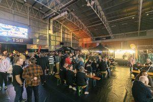 Colorful indoor scene at Taranaki Beer Festival with people enjoying craft beers and live entertainment.