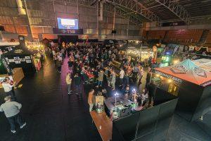 Festive indoor scene at the Taranaki Beer Festival showcasing craft beer stalls and crowds of attendees.