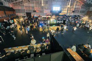 Vibrant Taranaki Beer Festival indoor event with beer stalls and lively crowd in a large venue.