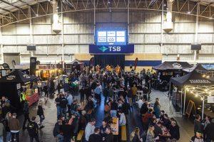 Vibrant scene at Taranaki Beer Festival showcasing craft beers, live music, and community fun in indoor arena.