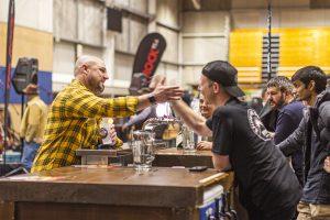 Vibrant beer festival scene with patrons enjoying craft beers at Taranaki Beer Festival, lively atmosphere and friendly bar service.