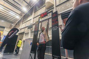 Vibrant scene at the Taranaki Beer Festival with a man hanging from a bar for a challenge.