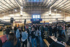 Busy crowd at Taranaki Beer Festival in an indoor venue, enjoying craft beer tastings and live music.