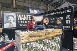 Vibrant Taranaki Beer Festival stand with brewery staff serving visitors at the event.