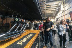 Vibrant scene at Taranaki Beer Festival with craft beers, lively crowd, and socialising in an indoor venue.