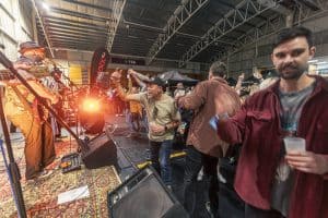 Vibrant crowd dancing and enjoying live music at the Taranaki Beer Festival in an indoor venue.