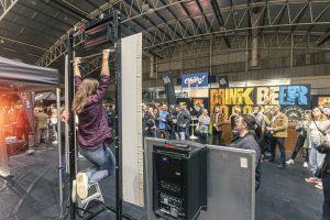 Young woman performing pull-up at Taranaki Beer Festival in New Zealand, popular event featuring craft beers and live entertainment.