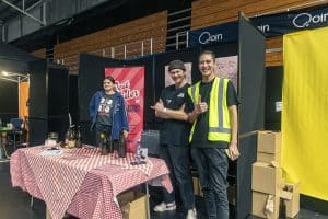 Vibrant beer festival scene with smiling vendors and craft beer bottles at Taranaki Beer Festival in New Zealand.