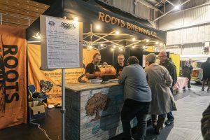 Cheers-filled Taranaki Beer Festival at Roots Brewing Co beer stand, showcasing craft beers and local brewing excellence in New Zealand.