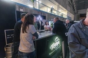 Fresh craft beer at the Taranaki Beer Festival in a lively indoor setting with beer enthusiasts sampling brews.