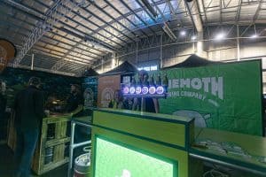 Vibrant indoor scene at Taranaki Beer Festival showcasing craft beer stalls and attendees enjoying local brews.