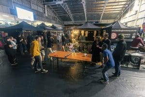 Enjoying craft beers at the Taranaki Beer Festival in an indoor venue with food trucks, live music, and local breweries.