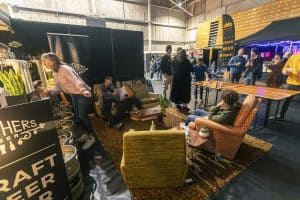 A vibrant indoor scene at Taranaki Beer Festival with people enjoying craft beers, socialising, and live entertainment.
