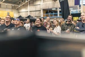Vibrant crowd enjoying the Taranaki Beer Festival with craft beers and lively atmosphere in an indoor venue.