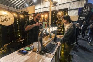 Fresh craft beers being served at Taranaki Beer Festival in a lively indoor setting with beer enthusiasts enjoying local brews.