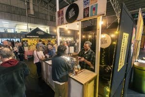 Vibrant Taranaki Beer Festival with craft beer stalls and enthusiastic attendees enjoying local brews.