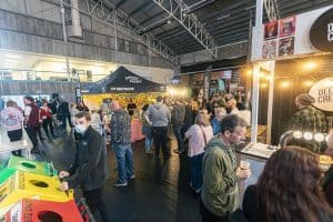 Colourful crowd enjoying Taranaki Beer Festival with craft beers & live entertainment in an indoor venue.