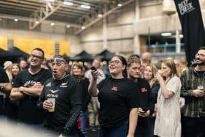 Vibrant crowd enjoying the Taranaki Beer Festival in an indoor venue with beer tents and lively atmosphere.