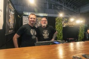 Casels NZ Pale Ale beer stand at the Taranaki Beer Festival, featuring brewers in front of Alchemist Mixology signage.