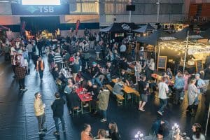 Crowd enjoying craft beers and live music at Taranaki Beer Festival in an indoor venue.