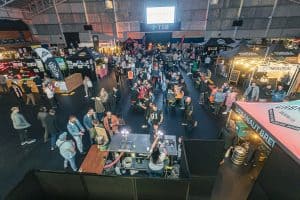 Busy Taranaki Beer Festival indoor event with craft beer stalls and attendees enjoying tasting experiences at the exhibition.