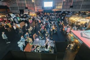 Vibrant indoor scene at Taranaki Beer Festival with craft beer stalls and crowds enjoying local brews.