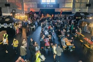 Vibrant crowd enjoying live music and craft beers at Taranaki Beer Festival in an indoor venue.