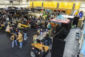 Vibrant indoor scene at Taranaki Beer Festival showcasing craft beer stalls and crowds enjoying local brews in a lively atmosphere.