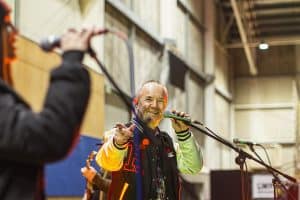 Vibrant male singer performing at Taranaki Beer Festival, enjoying craft beer and local entertainment in an industrial venue.