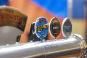 Bright beer tap handles showcasing Emersons Pale Man, Wessure, and other craft beers at Taranaki Beer Festival.
