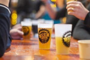 Full Beer Festival Taranaki beer glasses at the outdoor event, highlighting craft beer culture and lively festival atmosphere.