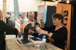 Golden beer being poured at Taranaki Beer Festival, showcasing local craft brews in a lively NZ event.