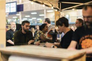 Variety of craft beers at Taranaki Beer Festival, inside a lively indoor venue.