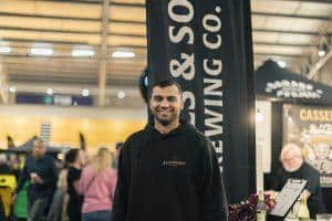Vegan man smiling at Taranaki Beer Festival with beer banners in the background.