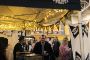 Taranaki Beer Festival atmosphere with people enjoying craft beers under decorated tent.
